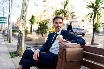 Mature businessman with takeaway coffee in street