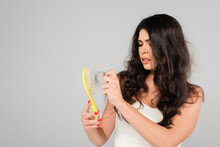 Brunette Woman With Hair Loss Problem Cleaning Hair Brush Isolated On Grey.