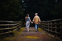 A Romantic Photo Of A Young Couple In A Beautiful Autumn Park, Walking Hand In Hand Down A Pathway Surrounded By Colorful Foliage