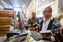 Smiling Business Owner Helping Customer Buying Books In Bookshop