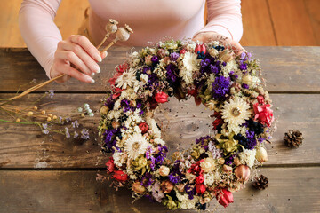 Wall Mural - Florist at work: woman shows how to make a door wreath with dry flowers and orher plants. Step by step, tutorial.