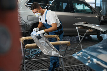 Male cleaning car parts before painting in garage