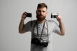 © Volodymyr - Professional bearded photographer holding a bunch of different vintage old cameras in a hands and on a shoulder.