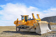 Big crawler dozer working on construction site or quarry. Mining machinery moving clay, smoothing gravel surface for new road. Earthmoving, excavations, digging on soils