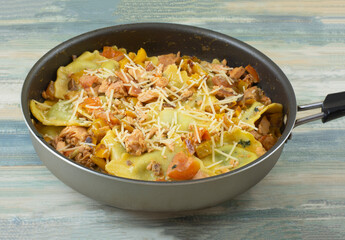 Spinach ravioli with salmon tomatoes and yellow bell pepper slices in nonstick skillet