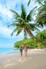 Wall Mural - A couple of men and women walking on a white tropical beach with palm trees in Phuket Thailand. Surin Beach phuket