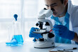 © kamiphotos - Lab assistant, a medical scientist, a chemistry researcher holds a glass tube through the blood sample, does a chemical experiment and examines a patient's blood sample. Medicine and research concept.