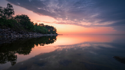 Wall Mural - wonderful colorful sunset on a calm sea with a rocky shore