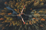 Fototapeta  - Highline over the forest. Rope walker walks on a rope at high altitude. Drone view. Slackline theme