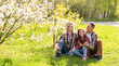 © Angelov - Outdoor portrait of happy young family playing in spring park under blooming tree, lovely couple with little child having fun in sunny garden