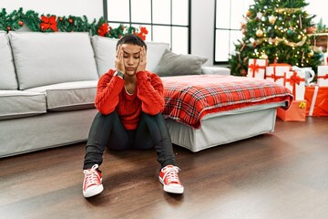 Sticker - Young hispanic woman unhappy sitting by christmas tree at home