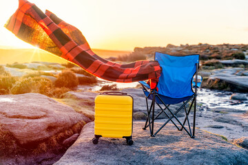 Blue beach chair, yellow  Suitcase, orange scarf in  the national park Peak District at sunrise. British cold winter. Local tourism concept.