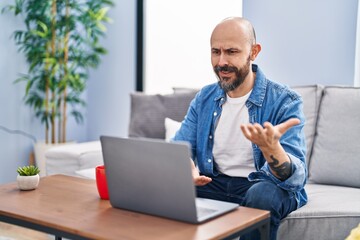 Wall Mural - Young bald man having video call sitting on sofa at home