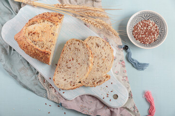 Wall Mural - Sliced fresh baked whole grain bread with flax seeds and sesame seeds on light blue board. Bakery products