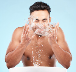 Poster - Face, water splash and skincare of man cleaning in studio isolated on a blue background. Hygiene, water drops and male model washing, bathing or grooming for healthy skin, facial wellness or beauty.