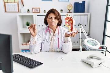 Poster - Middle age hispanic doctor woman holding coronavirus infection nasal test depressed and worry for distress, crying angry and afraid. sad expression.