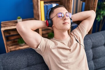 Sticker - Young hispanic man listening to music sitting on sofa at home