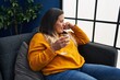 © Krakenimages.com - Young beautiful plus size woman drinking wine sitting on sofa at home
