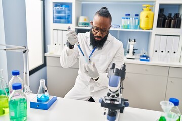 Sticker - Young african american man wearing scientist uniform using pipette at laboratory