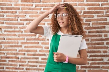 Poster - Young caucasian woman holding art notebook very happy and smiling looking far away with hand over head. searching concept.