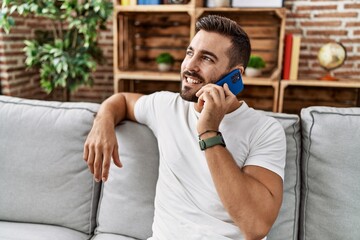 Poster - Young hispanic man smiling confident talking on the smartphone at home