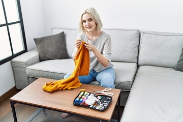 Poster - Young caucasian woman smiling confident sewing using needle and thread at home