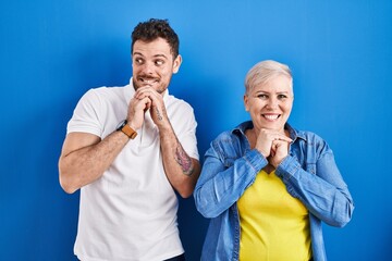 Sticker - Young brazilian mother and son standing over blue background laughing nervous and excited with hands on chin looking to the side