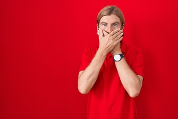 Poster - Caucasian man with mustache standing over red background shocked covering mouth with hands for mistake. secret concept.