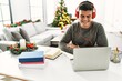 © Krakenimages.com - Young hispanic man studying sitting by christmas tree at home