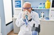 © Krakenimages.com - Senior man wearing scientist uniform using napkin at laboratory