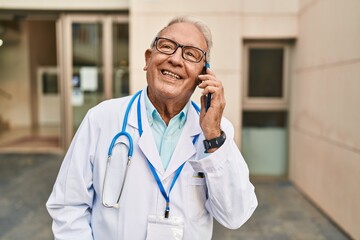 Canvas Print - Senior man wearing doctor uniform talking on the smartphone at street