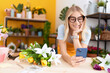 © Krakenimages.com - Young blonde woman florist using smartphone leaning on table at flower shop