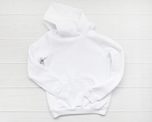 White fashionable kid sweatshirt with a hood with clothes hanger on white background top view. Fashionable unisex clothing, hoodie, casual youth style, sports. Blank hoody mock up 
