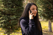 © Designerant - Talking to phone, caucasian brunette woman talking to phone. Side view portrait of millennial lady using smartphone, making call, seriously listening. Walking outdoors on street in fall day time.
