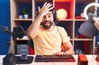 Hispanic man with beard playing video games with headphones surprised with hand on head for mistake, remember error. forgot, bad memory concept.