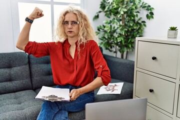 Wall Mural - Middle age psychologist woman at consultation office strong person showing arm muscle, confident and proud of power