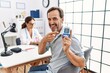 © Krakenimages.com - Middle age man at doctor clinic holding glucose meter device smiling happy pointing with hand and finger