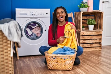 Sticker - Young african american with braids holding magnifying glass looking for stain at clothes smiling and laughing hard out loud because funny crazy joke.