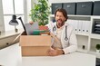 Handsome middle age doctor man holding box with items sticking tongue out happy with funny expression.