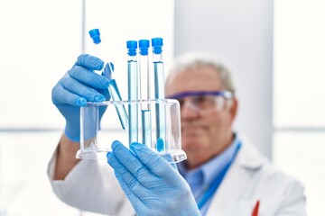 Sticker - Middle age grey-haired man wearing scientist uniform holding test tube at laboratory