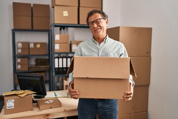 Sticker - Senior man working at small business ecommerce holding carboard bx winking looking at the camera with sexy expression, cheerful and happy face.