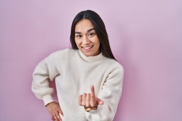 Poster - Young south asian woman standing over pink background beckoning come here gesture with hand inviting welcoming happy and smiling