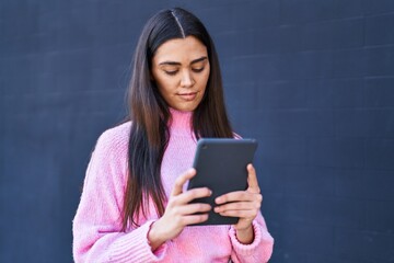 Wall Mural - Young hispanic woman using touchpad at street