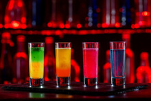 Cocktails Party Shots And Shooters On Bar Counter In A Restaurant, Pub. Miniature Mixed Drinks. Alcoholic Cooler Beverage At Nightclub On Dark Background
