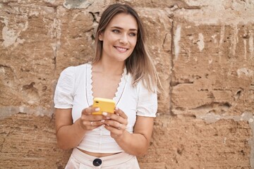 Sticker - Young caucasian woman smiling confident using smartphone over isolated brick background