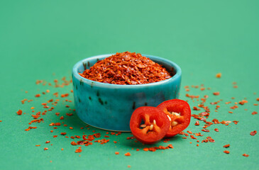Wall Mural - Bowl of chipotle chili flakes on green background