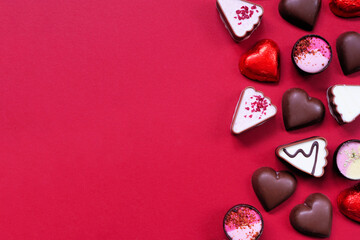 Wall Mural - Valentines Day chocolate side border. Red and pink heart theme. Above view on a red paper background with copy space.