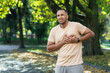 Hispanic athlete in the park has severe chest pain, man has a heart attack while jogging and doing fitness and exercise in the park outdoors.