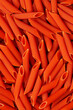 Uncooked red lentils pasta. Close up image of red penne italian pasta. 
