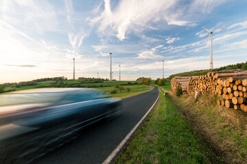 Wall Mural - car on the road in the countryside with the wind turbines in the background